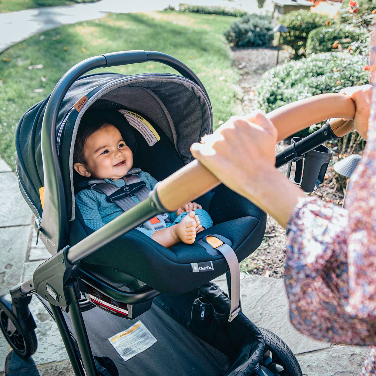 Baby smiling in a Chicco infant car seat & stroller frame made with non-toxic, flame-retardant-free materials