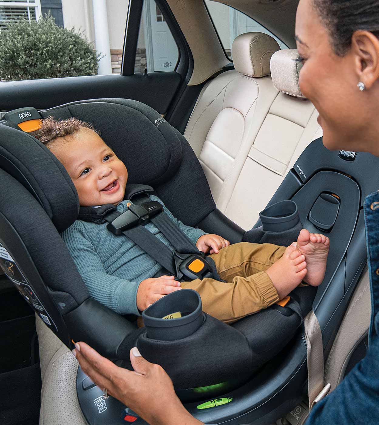 Caregiver interacting with a baby in a Chicco rotating convertible car seat turned toward the car door.