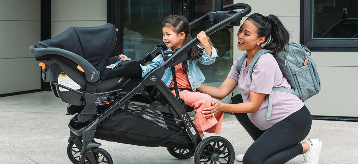 An adult with a child and an infant car seat attached to a Chicco double stroller