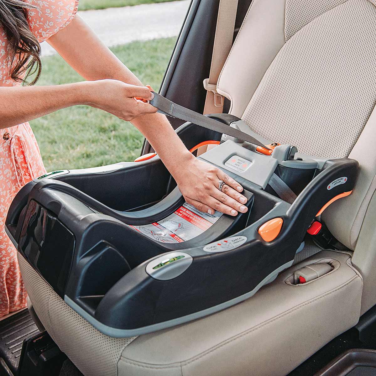 Person securing a Chicco KeyFit 30 infant car seat base on a vehicle seat