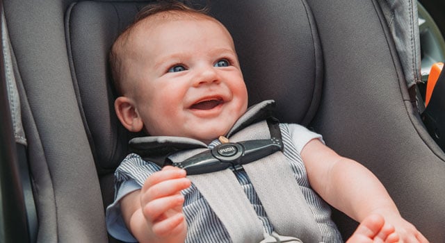Smiling infant secured in a Chicco infant car seat