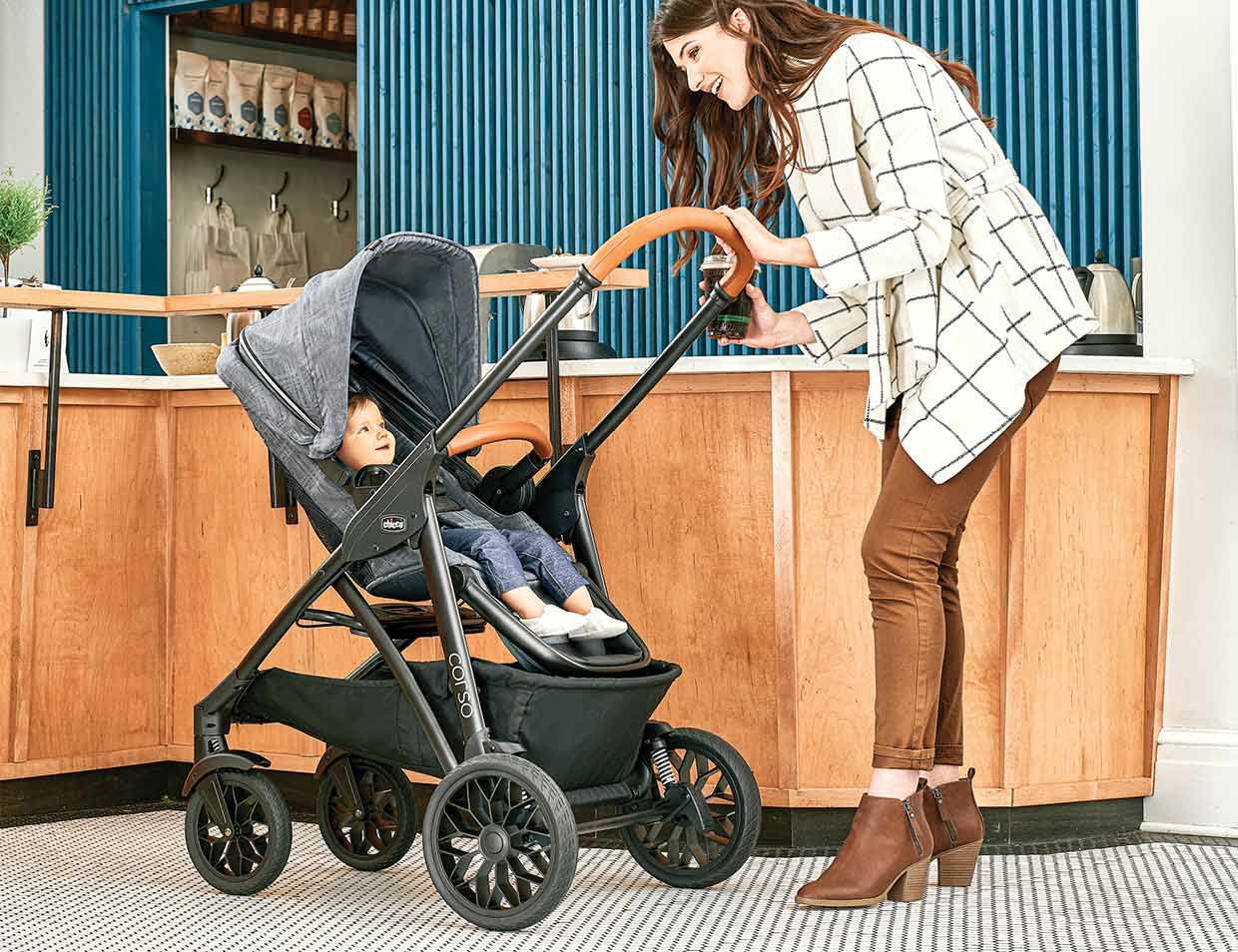 A mother checks on her child who is seated in a Chicco Corso LE Modular Stroller in the parent-facing position.