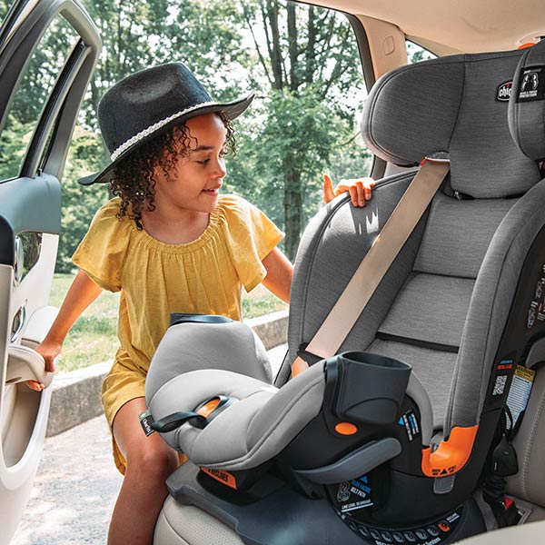 Child climbing into a Chicco OneFit ClearTex All-in-One car seat inside a vehicle